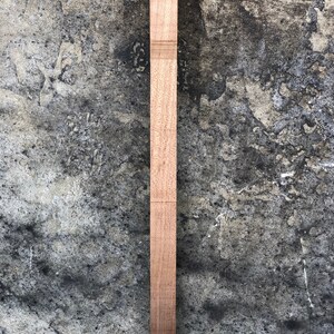 Peut inclure: Une longue et fine pi&egrave;ce de bois avec une finition naturelle. Le bois est lisse et de couleur brun clair.