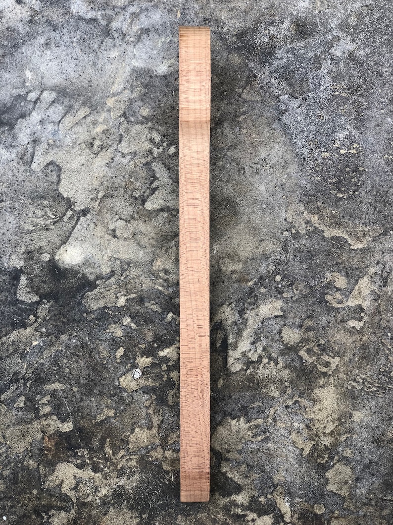 Peut inclure: Une &eacute;bauche de manche de guitare en bois brun clair, pr&ecirc;te &agrave; &ecirc;tre fa&ccedil;onn&eacute;e et finie. Le manche est lisse et pr&eacute;sente une l&eacute;g&egrave;re courbure en haut.