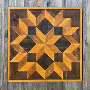 May include: A geometric wall art piece made of wood with a starburst pattern. The wood is stained in shades of brown and yellow.