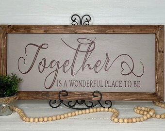 May include: A rectangular wooden sign with a brown frame and a light gray background. The sign features the word "Together" in a cursive font, with the phrase "is a wonderful place to be" below it. Decorative home decor.