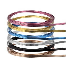 May include: A selection of coiled, flat metal strips in a range of colours: pink, gold, blue, silver, black, and bronze. These flexible strips are likely intended for crafting or decorative use, and are presented against a white background.