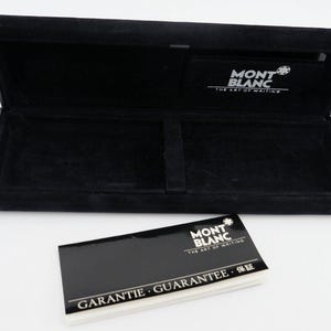 Op de afbeelding: Zwarte doos met een fluwelen binnenkant en een zwarte leren buitenkant. De doos is open en heeft een Mont Blanc logo aan de binnenkant. De doos is voor een pen en bevat een garantiekaart.