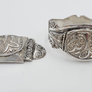 May include: Two silver bracelets with intricate designs. The bracelets are both oval shaped and feature a repeating pattern of swirls and lines. The bracelets are made of sterling silver and are in excellent condition.