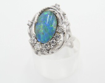 May include: A silver ring with a large oval blue opal gemstone surrounded by smaller clear gemstones in a floral design.