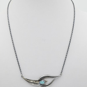 May include: A silver chain necklace with a pendant featuring a pear-shaped opal set in a silver and gold swirl design.