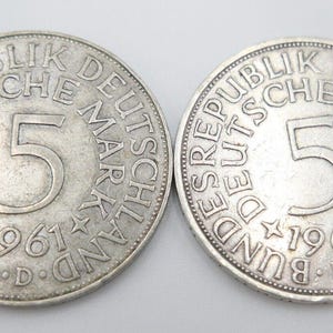Könnte beinhalten: Zwei deutsche 5-Deutsche-Mark-Münzen aus Silber aus dem Jahr 1961. Die Münzen zeigen auf der Vorder- und Rückseite den Text "Bundesrepublik Deutschland" und "5 Deutsche Mark".