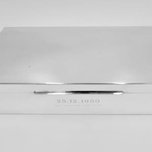 May include: A silver rectangular box with a hinged lid. The box has an inscription on the bottom that reads "25.12.1950".