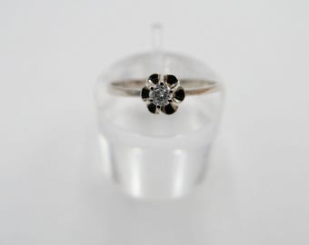 Puede incluir: Un anillo de plata con un solo diamante redondo engastado en un diseño con forma de flor.