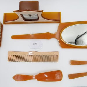 Könnte beinhalten: Ein Set aus sieben Vintage-Badaccessoires aus braunem und weißem Kunststoff. Das Set enthält eine Haarbürste, einen Kamm, einen Spiegel, zwei kleine Kämme und einen Schuhlöffel. Das Set ist in gutem Zustand mit einigen kleinen Gebrauchsspuren.
