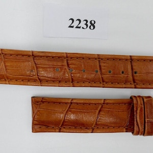 May include: A brown leather watch strap with a crocodile pattern. The strap is 22mm wide and has a quick release spring bar system. The strap is made of genuine leather and is designed for use with watches that have a 22mm lug width.