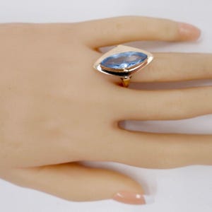 May include: A gold ring with a light blue marquise-shaped gemstone set in a prong setting.