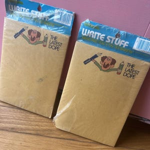 May include: A rustic wooden sign with the text "Welcome" in a handwritten style. The sign is painted white with a distressed finish, and features a decorative floral element in the corner. The background is a blurred image of a wooden surface.