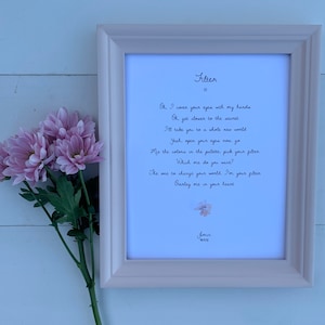 May include: A framed print with the word "Filter" and lyrics in black script. The frame is light pink, and a bouquet of pink flowers rests beside it. The text includes the name "Jimin" and Korean characters.