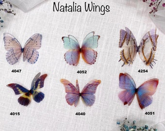 May include: Six butterfly wings in various colors and patterns, including purple, blue, and yellow. The wings are arranged in a grid pattern with the numbers 4047, 4052, 4254, 4015, 4040, and 4051 underneath each wing. The text "Natalia Wings" is at the top of the image.