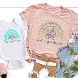 May include: A pink and white t-shirt set with a castle and rainbow design. The shirts say "Most Magical Day Ever".