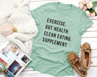 May include: A green t-shirt with the text "EXERCISE. GUT HEALTH. CLEAN EATING. SUPPLEMENT." printed in black.