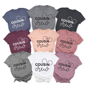 May include: Eight t-shirts in various colors with the text "COUSIN crew" in white and black lettering. The shirts feature a Mickey Mouse ear design and a bow.