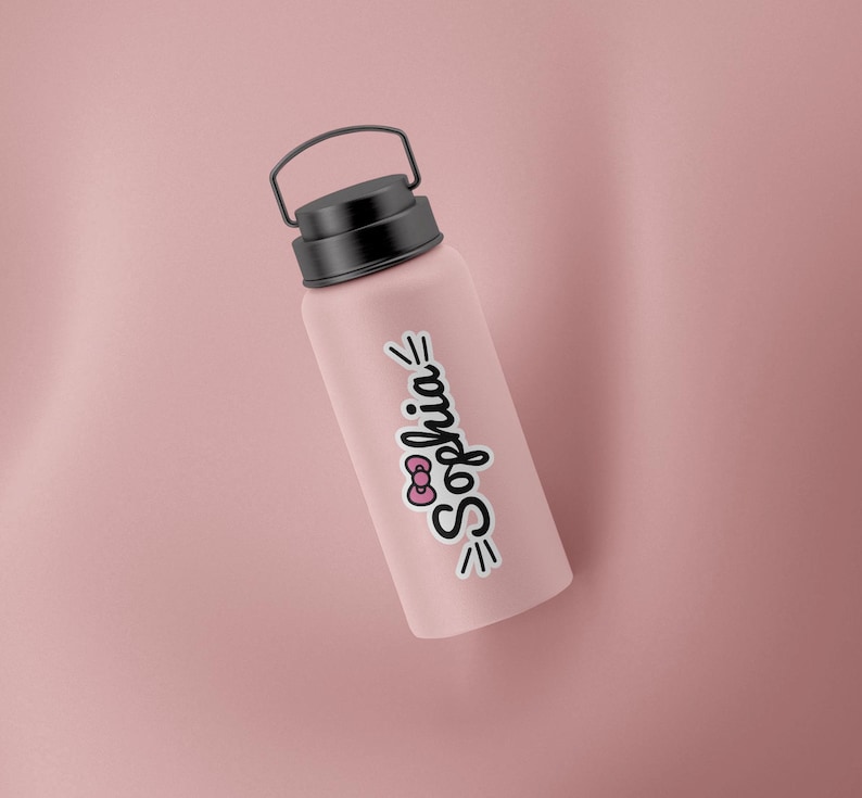 May include: A matte dusty pink water bottle with a black screw-top lid and a carrying handle. A white sticker is applied to the side featuring the name Sophia in black cursive script, accented by a small pink bow and black decorative lines.