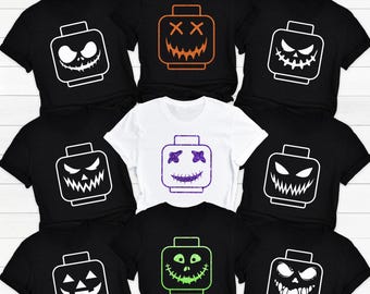 May include: Nine black and white t-shirts with a white outline of a Lego brick with a pumpkin face. The pumpkin faces have different expressions, including a smiling face, a frowning face, and a surprised face. The t-shirts are a fun and festive way to celebrate Halloween.