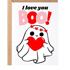 May include: A white ghost with a pink heart and a red heart in its hands. The ghost is wearing a crown of red hearts. The text "I love you BOO!" is written in black and pink letters above the ghost.