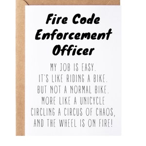 May include: A white card with black text that reads "Fire Code Enforcement Officer". The text continues with a humorous description of the job: "My job is easy. It's like riding a bike, but not a normal bike. More like a unicycle circling a circus of chaos, and the wheel is on fire!"