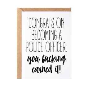 May include: A greeting card with a white interior and a brown kraft paper envelope. The card reads "CONGRATS ON BECOMING A POLICE OFFICER. you fucking earned it!" in black, handwritten-style font.
