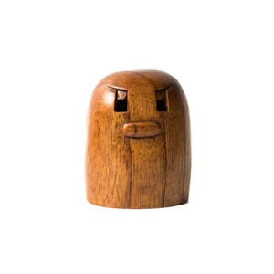 May include: A wooden figurine with a carved face, featuring two eyes and a mouth. The figurine is brown and has a smooth, polished finish.