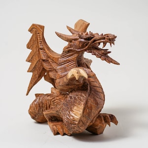 May include: A hand-carved wooden dragon figurine with intricate details. The dragon is brown and has a fierce expression with sharp teeth and claws.