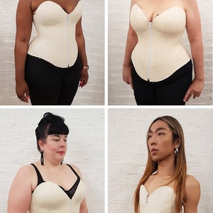 Op de afbeelding: Vier mensen dragen een witte strapless corset met een rits aan de voorkant. De korsetten zijn gemaakt van een gladde stof en hebben een lichte glans. De mensen zijn van verschillende lichaamsvormen en etniciteiten.