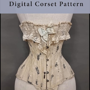 Puede incluir: Un corsé crema con patrones florales negros, exhibido en un maniquí. Cuenta con un ribete de encaje, un lazo azul claro y cierres metálicos. El texto "Digital Corset Pattern" se muestra encima del corsé.