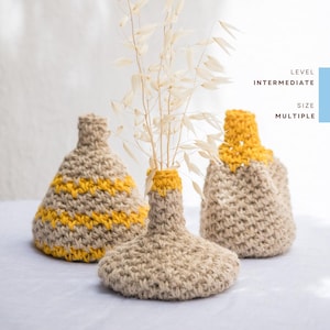 Könnte beinhalten: Drei handgefertigte Häkelvasen in Beige und Gelb. Die Vasen haben ein strukturiertes Aussehen und unterschiedliche Designs, wobei eine horizontale gelbe Streifen aufweist. Der Text rechts lautet "LEVEL INTERMEDIATE SIZE MULTIPLE."