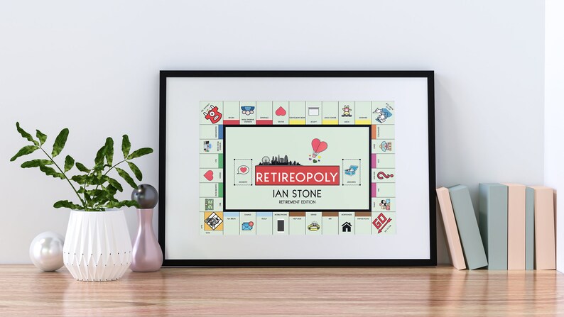 May include: A framed print of a personalized "Retirepoly" board game, featuring the name "Ian Stone" and the text "Retirement Edition". The board game is a parody of Monopoly, with a green background and colorful squares.