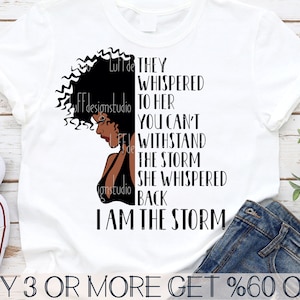 Peut inclure: Un t-shirt blanc avec une silhouette noire d'une femme aux cheveux bouclés et le texte "They whispered to her you can't withstand the storm she whispered back I am the storm!"