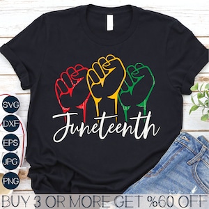 May include: Black t-shirt featuring three raised fists in red, yellow, and green. The text "Juneteenth" is written in white cursive below the fists.