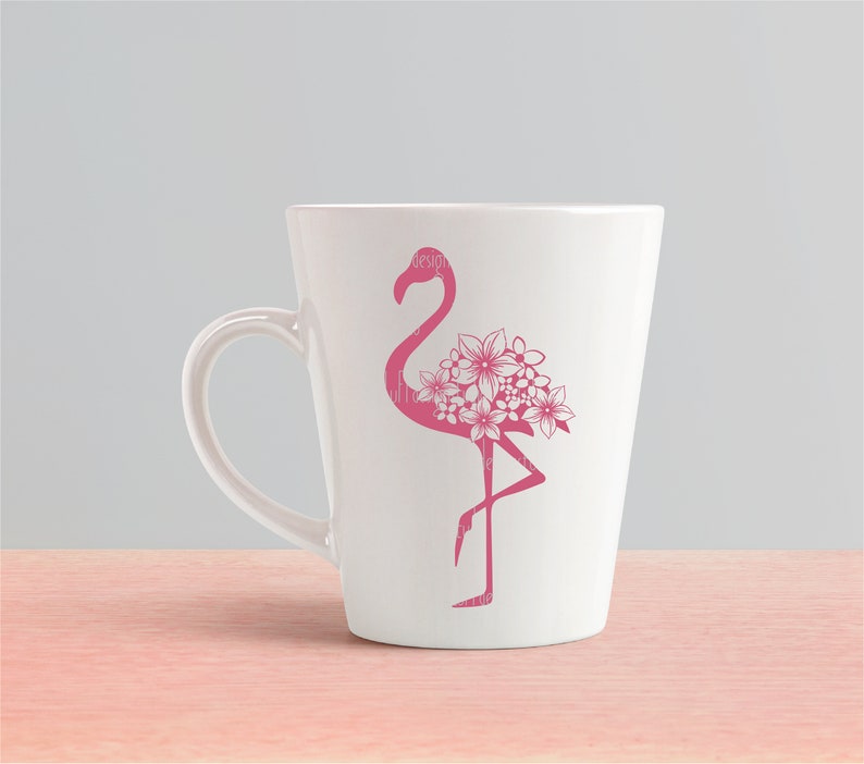 May include: A white ceramic mug with a pink flamingo silhouette design. The flamingo has flowers on its back.