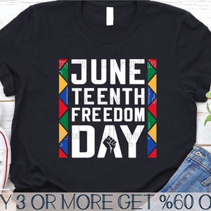 May include: Black t-shirt with a white graphic that says "Juneteenth Freedom Day" with a raised fist in the middle of the text. The graphic is surrounded by a colorful border of red, yellow, green, and blue triangles. The text "BUY 3 OR MORE GET %60 OFF" is at the bottom of the image.