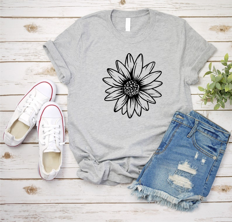 May include: A gray t-shirt with a black daisy graphic. The t-shirt is paired with denim shorts and white sneakers.