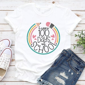 May include: White t-shirt with a colorful graphic that says "happy 100 days of school" with a rainbow and hearts.