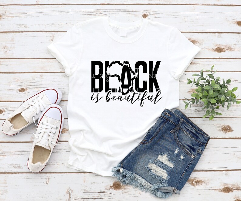 May include: White t-shirt with black text that reads "Black is beautiful" with a stylized outline of the continent of Africa in the middle of the word "Black".