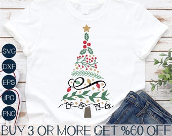 May include: A white t-shirt with a green, red, and gold Christmas tree design. The tree is decorated with lights, stars, and berries. The text "BUY 3 OR MORE GET %60 OFF" is printed at the bottom of the shirt.
