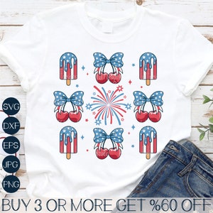 May include: A white t-shirt with a design of red, white, and blue popsicles, cherries with bows, and fireworks. The text "BUY 3 OR MORE GET %60 OFF" is at the bottom of the shirt.