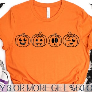 May include: Orange t-shirt with four black pumpkin faces with different expressions. The text "BUY 3 OR MORE GET %60 OFF" is at the bottom of the shirt.