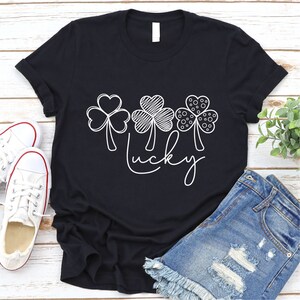 May include: Black t-shirt with a white design of four shamrocks and the word "lucky".