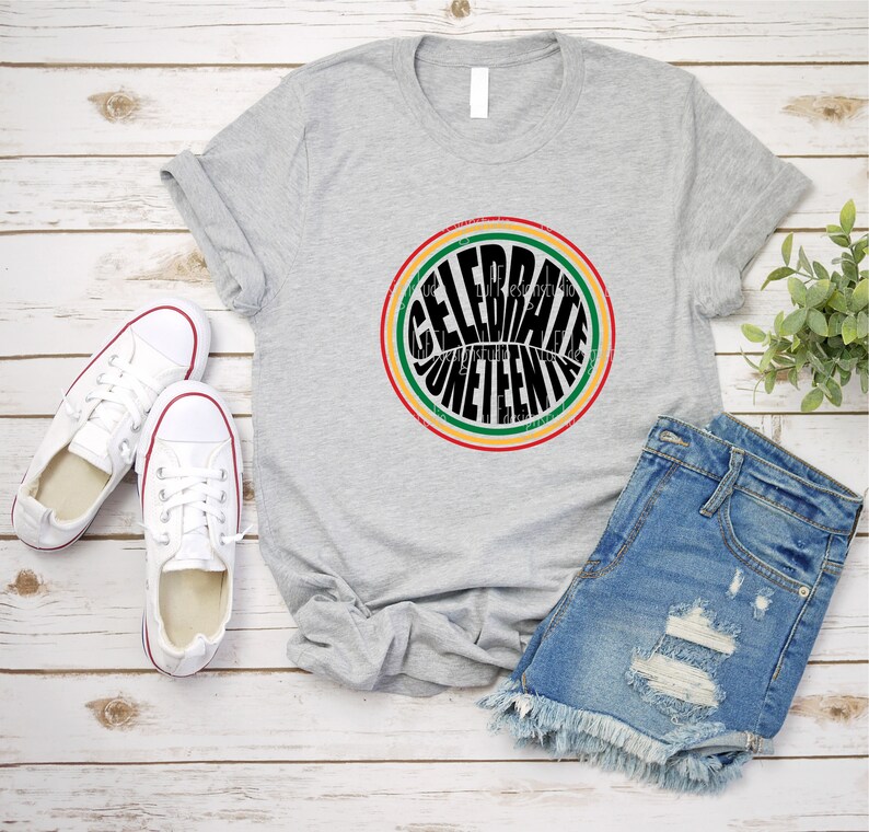 K&ouml;nnte beinhalten: Ein graues T-Shirt mit einem schwarzen Kreis-Motiv, auf dem in einer Retro-Schriftart "Celebrate Juneteenth" steht. Der Kreis ist mit roten, gelben und gr&uuml;nen Streifen umrandet.