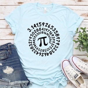 May include: A light blue t-shirt with a black graphic of the mathematical constant pi, surrounded by a circle of numbers. The numbers represent the first digits of pi.