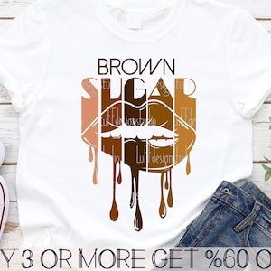 Peut inclure: Un t-shirt blanc avec un graphique brun qui coule et qui dit "BROWN SUGAR" dans une police de caractères stylisée. Le graphique est une image stylisée de lèvres avec de la peinture brune qui coule.