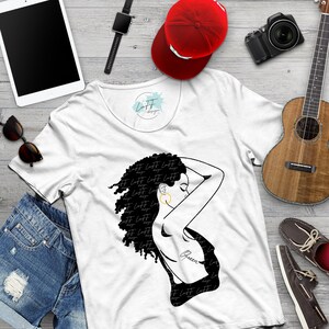 May include: White t-shirt with a black graphic of a woman with curly hair, gold hoop earring, and the word "Queen" on her back. The shirt is surrounded by accessories including a red baseball cap, sunglasses, and a ukulele.