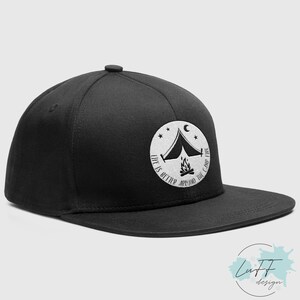 Op de afbeelding: Zwarte en witte geborduurde flat brim baseballcap met een wit cirkelontwerp met een tent, kampvuur, sterren en de tekst "Life is better around the campfire".
