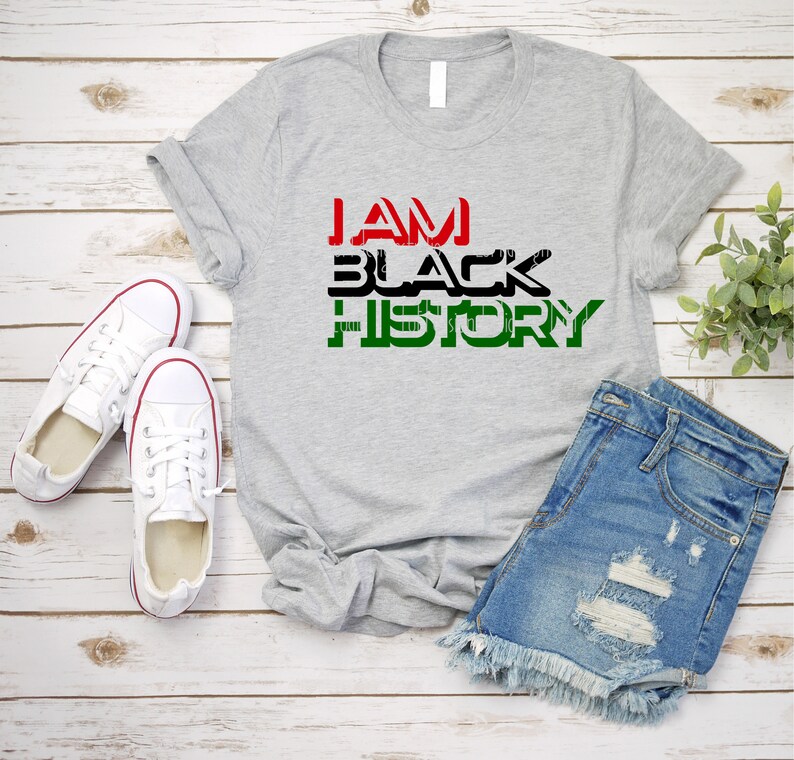 May include: A gray t-shirt with the text "I AM BLACK HISTORY" in black, red, and green letters.