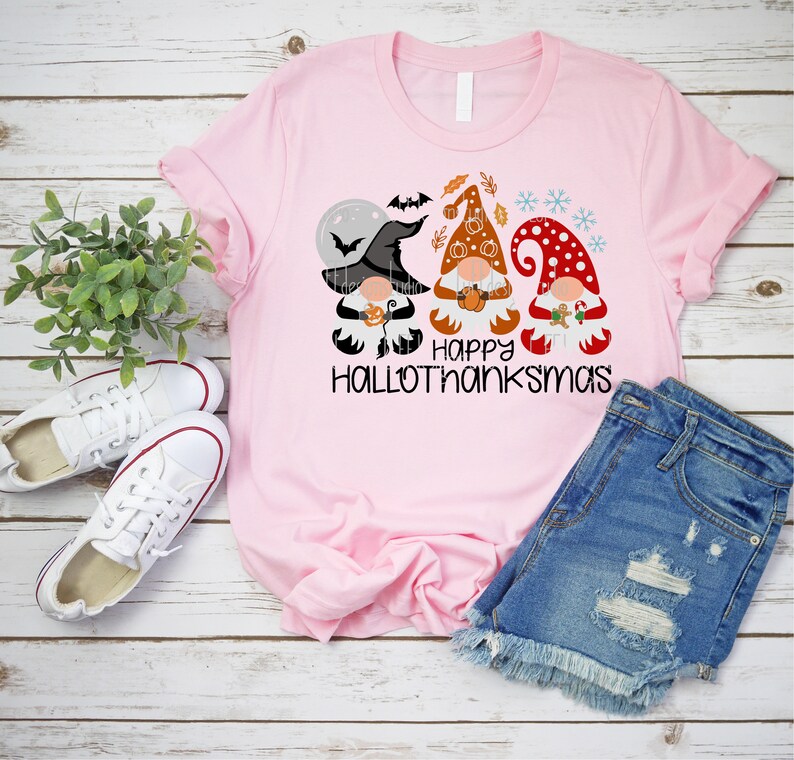 May include: Pink t-shirt with a graphic of three gnomes dressed for Halloween, Thanksgiving, and Christmas. The text "Happy Hallothanksmas" is printed below the gnomes.